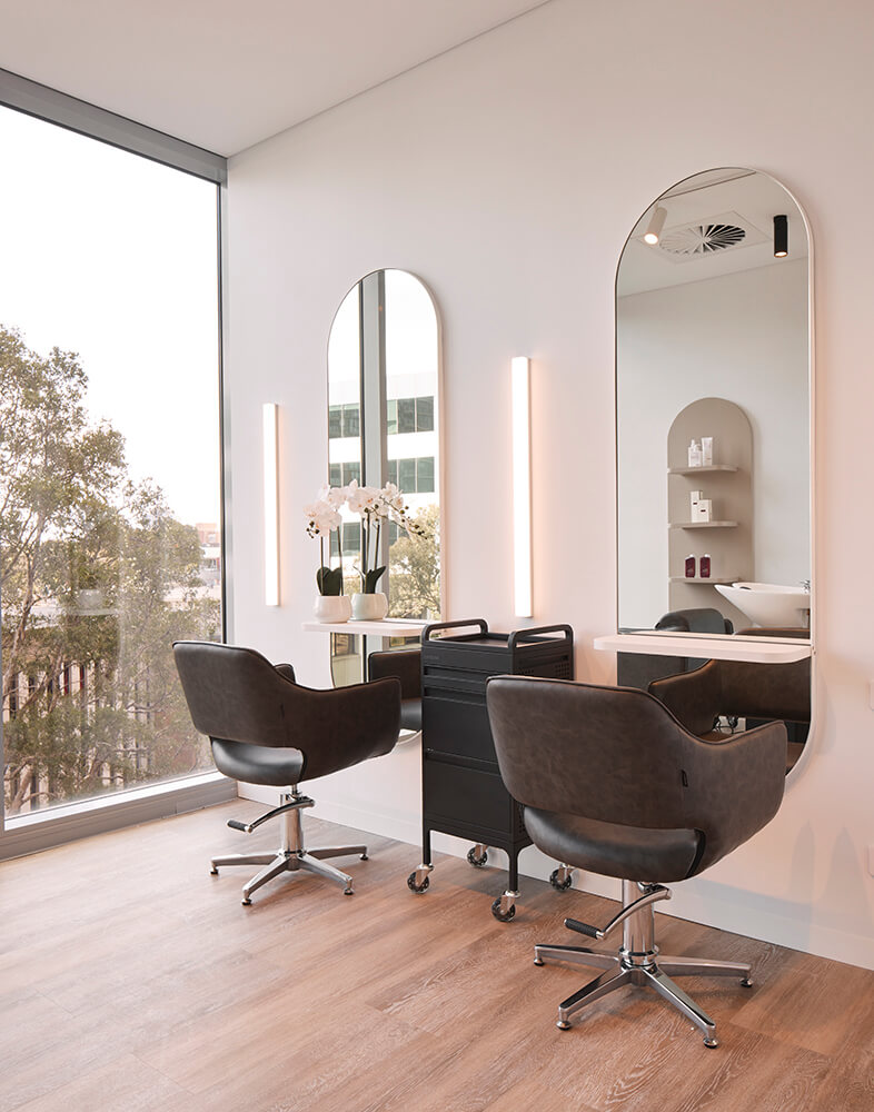 Hair salon with two chairs and mirrors next to a large window in salon lane